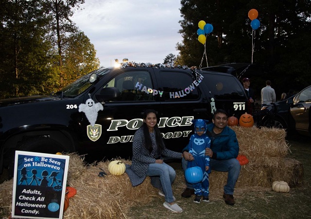 Family poses in front of decorated police cruiser at Truck or Treat